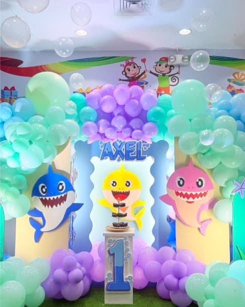 A Baby Shark party setup with mint and lilac balloons and shark cut-outs
