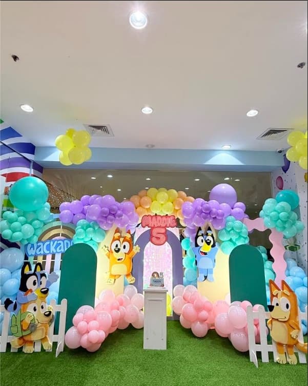 A Bluey party setup with pastel balloon arches and character cut-outs