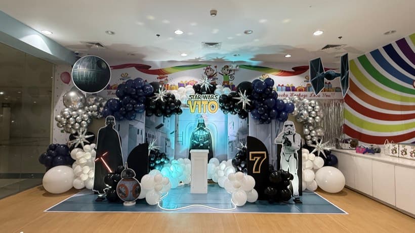 A Star Wars party setup with navy, black and silver balloons and a lit backdrop