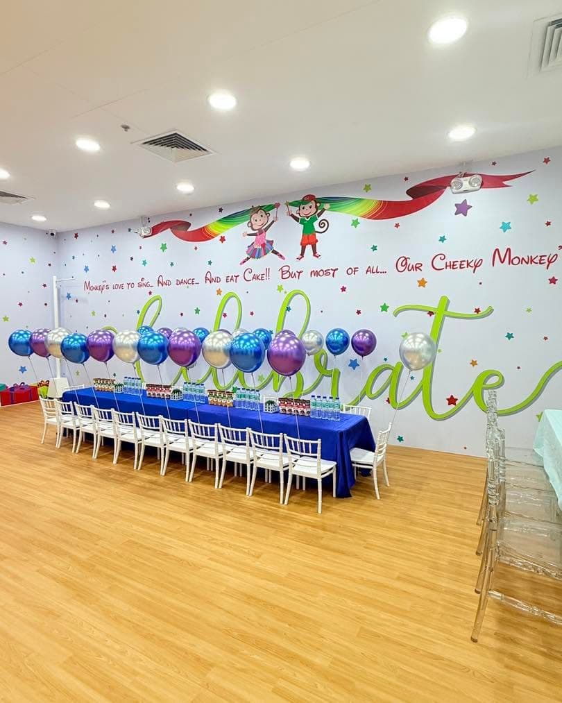A party room laid out with a long table and balloons