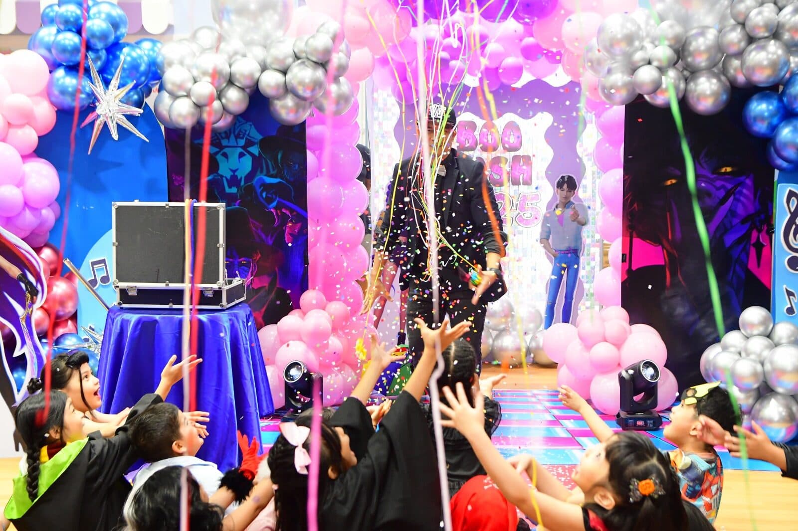 Kids reaching for confetti at the finale of a magic show